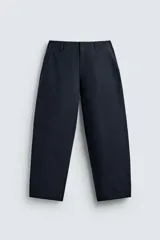Pantalón de corte balloon fit, color negro, con bolsillos laterales de vivo y bolsillos traseros con solapa. Presenta cierre frontal con cremallera y botón.