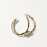 Brazalete rígido dorado con una piedra verde en forma de lágrima.