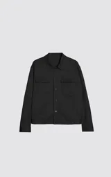 Chaqueta de corte regular crop confeccionada en microfibra pesada levemente elastizada. Presenta un diseño inspirado en la campera de jean clásica, con cuello volcado, cierre frontal mediante broches snap a tono y dos bolsillos delanteros con solapa.