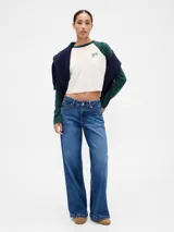 Remera de manga larga estilo raglán con cuerpo en color crema y mangas en color verde oscuro. Presenta un pequeño logo estampado en el pecho.