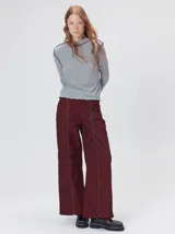 Polera de manga larga confeccionada en tela rib color bordó, con cuello alto y hombreras. Presenta costuras a la vista con pespuntes en hilo de color contrastante en el cuello, puños, hombros y ruedo.