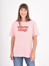 Remera de algodón color rosado con estampa frontal en color rojo con la frase Warm Hugs en tipografía retro.