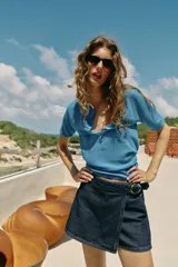 Falda pantalón cruzada de denim en color celeste, con diseño cruzado al frente, cierre frontal oculto y hebilla decorativa redonda en la cintura.