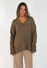 Sweater de punto color bordó con cuello en V, manga larga con puños acanalados y detalle de franja en contraste. Presenta un diseño holgado con aberturas laterales.