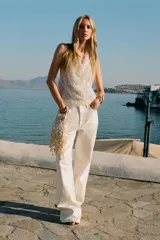 Top blanco con lentejuelas plateadas, de cuello halter y espalda descubierta.