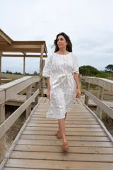 Túnica blanca con rayas verticales finas color dorado, corte holgado, mangas cortas amplias y lazo en la cintura.