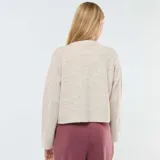 Chaqueta color beige de tejido de punto, corte cropped, con cuello redondo y cierre frontal con botones.