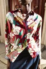 Camisa de cuello solapa y manga larga con puños a rayas. Confeccionada en tejido satinado con estampado floral multicolor sobre base roja. Cierre frontal con botones forrados.