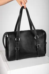 Cartera tipo bolso de mano y hombro de cuero color bordó, con diseño estructurado, doble asa corta y detalles de correas con hebillas metálicas en el frente.