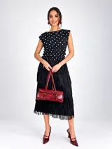 Blusa sin mangas de viscosa color negro con estampado de lunares blancos, cuello redondo y cintura fruncida con elástico.