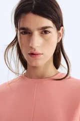 Top de manga corta color rosado, con cuello redondo y pinzas moldeadoras en la cintura que generan un bajo acampanado.