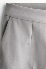 Pantalón sastrero gris de tiro alto, con cierre y corchete ocultos, piernas rectas con raya marcada al frente y en la espalda, y bolsillos laterales al bies.