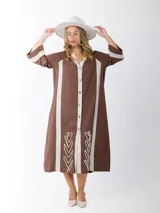 Vestido camisero marrón con rayas verticales color crema, de corte recto y largo midi. Presenta cuello en V, cierre frontal con botones y bordados en el ruedo.