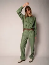 Camisa verde de cuero sintético con cuello marrón, cierre frontal con botones, dos bolsillos con solapa en el pecho y cinturón marrón.