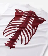 Remera de corte oversized confeccionada en mezcla de algodón y poliéster, con cuello redondo y mangas cortas. Presenta un estampado frontal con lettering estilo gótico y un estampado de esqueleto en la espalda.