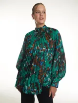 Blusa de gasa plisada con estampado abstracto en tonos verdes, azules y marrones. Presenta cuello alto, mangas largas abullonadas con puños abotonados y un corte holgado con caída fluida.