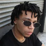 Lentes de sol con armazón metálico plateado y cristales ovalados oscuros. Diseño moderno y minimalista con protección UV400.