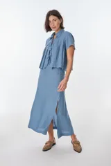 Falda larga color rojo ladrillo, de corte recto y tiro alto, con abertura lateral pronunciada.