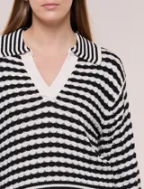 Blusa tejida de punto a rayas horizontales blancas y negras, con cuello polo y escote en V profundo. Presenta hombros caídos, mangas 3/4 estilo campana y corte holgado.