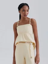 Blusa color beige de lino con breteles finos ajustables y detalle de botones decorativos.