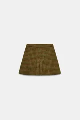 Falda corta de tiro medio con diseño evasé, confeccionada en tejido de punto con estampado de cuadros en tonos verde y marrón.