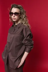 Camisa de manga larga con diseño de rayas verticales y horizontales en color marrón. Presenta un corte oversize con hombros caídos, cuello clásico y cierre frontal con botones.