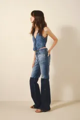 Pantalón de jean con tiro medio, corte ajustado hasta la rodilla y pierna acampanada. Presenta un diseño de tres tonos de azul logrado mediante procesos de lavado y recortes laterales a contratono.