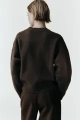 Jersey de cuello redondo y manga larga, confeccionado en tejido de punto suave con acabados en rib en cuello, puños y bajo.