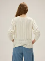 Cardigan de punto color blanco marfil, con escote en V, mangas largas con detalles de tejido calado y cierre frontal de botones con efecto madera.