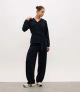 Campera deportiva de estilo utilitario color negro, confeccionada en tejido técnico. Presenta capucha, cierre frontal con botones, bolsillos con solapa en el pecho y lazo ajustable en la cintura. Posee mangas largas con puños y diseño liso.