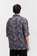 Camisa oversize de manga corta con cuello clásico y estampado abstracto en tonos grises.