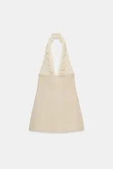 Vestido corto con escote halter pronunciado y hombros descubiertos, de color beige en la parte inferior y diseño a rayas con volantes en la parte superior.