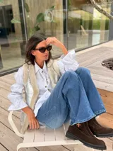 Chaleco reversible de corte recto, con un lado en acabado metalizado plateado y el otro en textura de corderito sintético color crema. Presenta bolsillos laterales y diseño sin mangas.