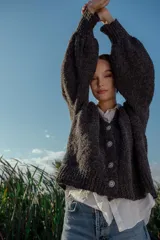 Cárdigan tejido de boucle color gris oscuro, con escote en V, mangas largas abullonadas y cierre frontal con botones grandes. Corte holgado.