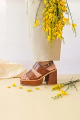 Sandalias de plataforma con taco cuadrado, confeccionadas en cuero con textura de reptil en color marrón. Presentan dos tiras anchas en el empeine y una tira ajustable con hebilla metálica en el talón.