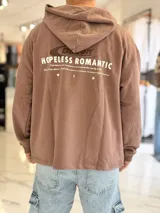 Hoodie oversize color marrón con capucha y estampado trasero con la frase 'Hopeless Romantic' y gráficos.