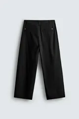 Pantalón chino de corte wide fit confeccionado en tejido de algodón. Presenta pliegues frontales, bolsillos laterales y bolsillos traseros de vivo, con cierre frontal de cremallera y botón.