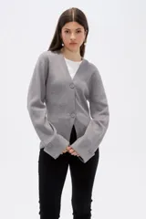 Saco de punto gris con cuello en V, cierre frontal con botones y mangas largas con puños anchos decorados con botones.
