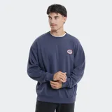 Buzo de cuello redondo marca Reef, color azul grisáceo, con diseño de calce holgado y parche circular con logo en el pecho.