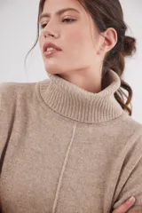 Polera de calce relajado con cuello alto, confeccionada en lana. Presenta un diseño bicolor con cuerpo en gris claro y mangas con estampado jacquard de arabescos en tonos tierra y negro. Incluye detalle de costura central vertical en el frente.