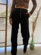 Pantalón negro de vestir, de corte recto, con bolsillos laterales y traseros. Se ajusta a la cintura con cinturón de cuero marrón.