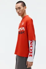 Remera de malla color rojo, con cuello en V, mangas cortas y corte oversized. Cuenta con diseño estampado frontal de Honda con banderas a cuadros y el logo de la marca.