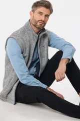 Chaleco de felpa gris con textura jaspeada, cuello alto y detalle de etiqueta de cuero sintético en la nuca.