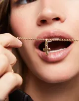 Dije charm de aleación de metales bañados en oro 18k con forma de cruz.