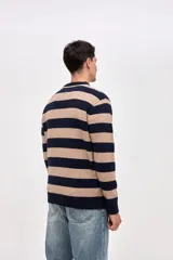 Buzo de punto con diseño de rayas horizontales en azul marino y beige, cuello redondo y puños acanalados. Presenta un pequeño bordado de estrella en la manga.