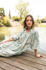 Vestido midi de corte camisero con estampado floral en tonos verde agua y crema. Presenta cuello a la base, cierre frontal con botones y mangas al codo con terminación elástica.