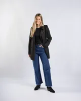 Campera tipo trench negra a la cadera, con solapa cruzada, doble botonadura frontal, hombreras y bolsillos delanteros con solapa.