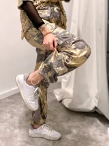 Pantalón cargo de tela satinada con estampado abstracto en tonos dorados y grises.