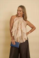 Blusa de cuello halter en color tostado, con diseño sin mangas y grandes volantes frontales en cascada.