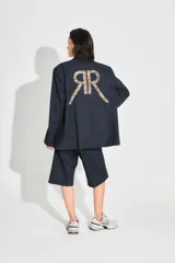 Saco sastrero de corte oversize, color negro, con cierre frontal de botones, bolsillos delanteros y forro interior de tafeta. Presenta una estampa grande en la espalda con las letras RR en diseño animal print.